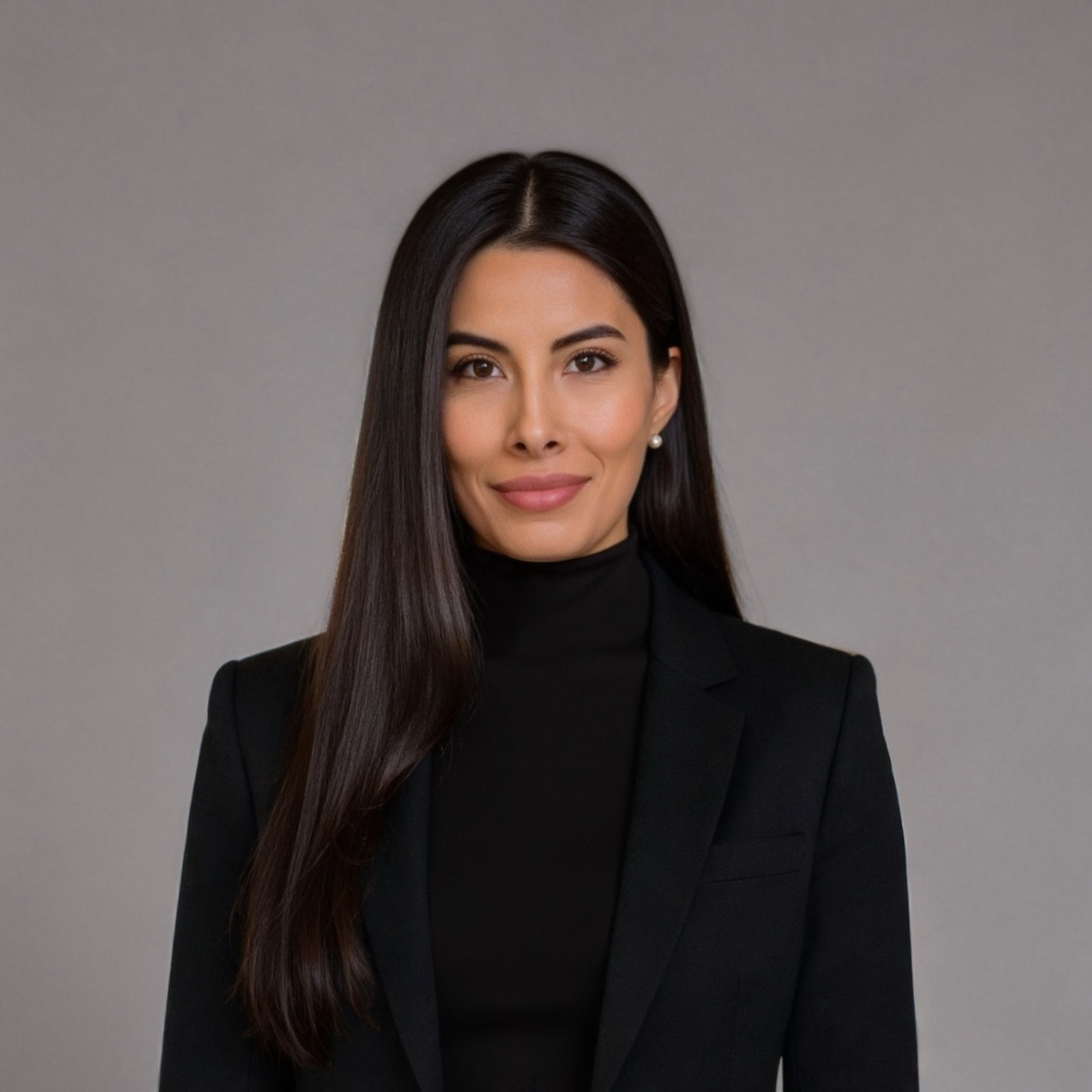 Ritratto di una donna sicura con lunghi capelli scuri che indossa un blazer nero e dolcevita in un ufficio moderno.